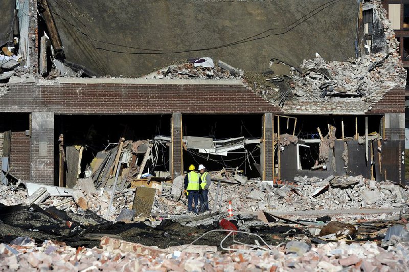 Inspectors stand in debris Saturday at the site of a gas explosion that leveled a strip club in Springfield, Mass., on Friday evening. 