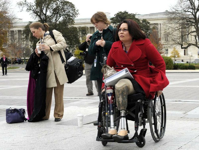 U.S. Rep.-elect Tammy Duckworth, D-Ill., who lost her legs in combat before turning to politics, arrives for a group photo on the steps of the Capitol earlier this month. 