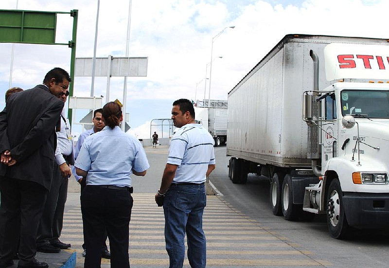 Attorney Emilio de La Rosa (left) and forensics expert Mario Gomez (right) talk to customs and court officials at the Las Americas Bridge in Juarez, Mexico, in July while reconstructing events that led to the arrest of trucker Jabin Bogan. 