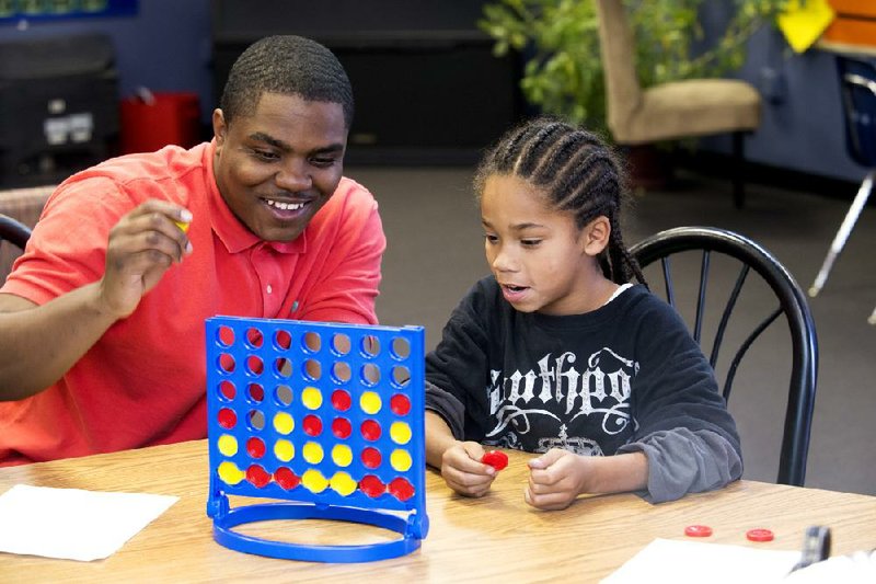 Dominique Rutledge, program coordinator at Our House in Little Rock, plays a game with Antonio Cloince at the children’s center on East Roosevelt Road last week. 