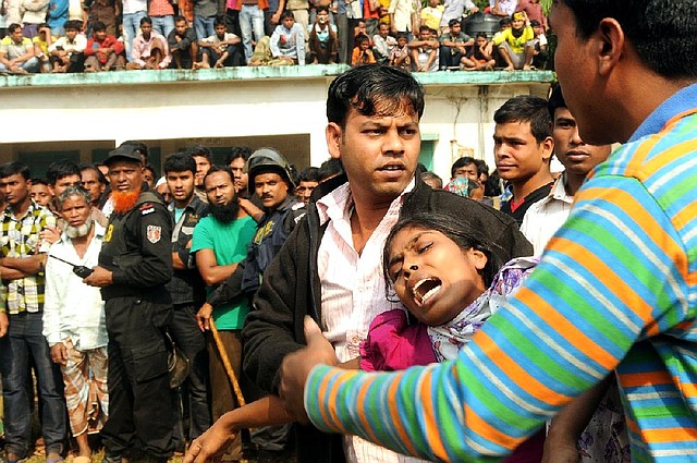 People console a woman Sunday whose relative was killed in a fire at a garment factory Saturday outside Dhaka, Bangladesh. 