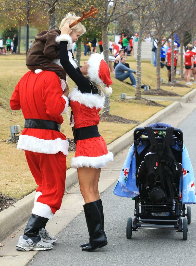 Michele Pyne (right) adjusts a pair of reindeer antlers for son Patrick, 5, as he rides on his father, Jeff’s, shoulders during the Arthritis Foundation’s 2011 Jingle Bell Run/Walk in Little Rock. 