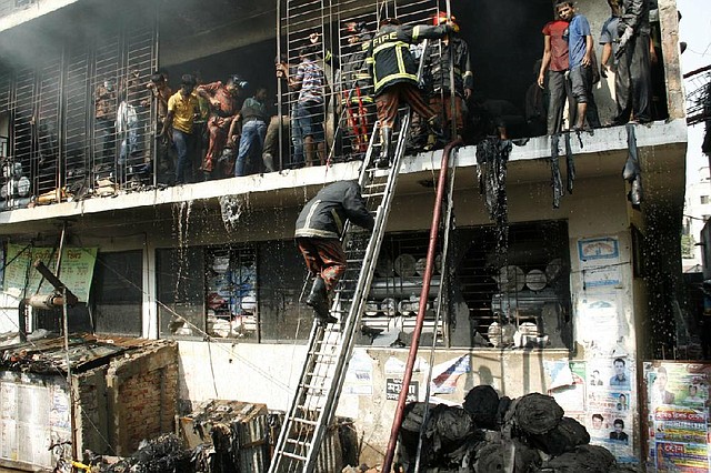 Bangladeshi firefighters and workers try to douse a fire at a garment factory Monday in Dhaka, Bangladesh. 