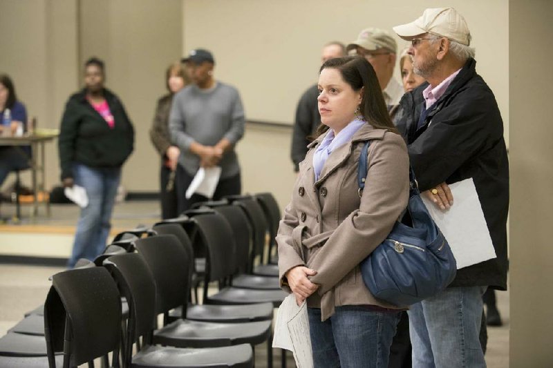 Katie Melton waits in line for an open voting booth at the Laman Library in North Little Rock on Monday afternoon. Long lines were common for early voting ahead of today’s runoff election, but they moved swiftly. 