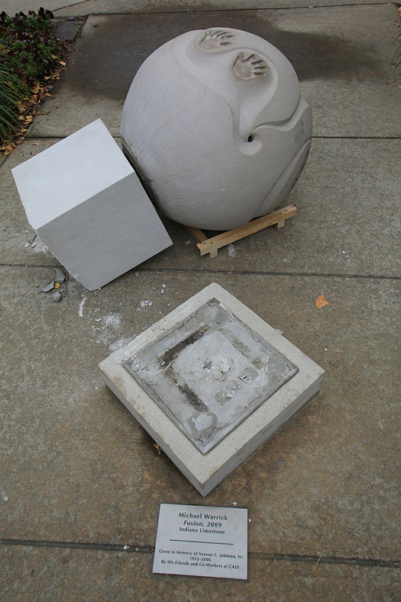 A sculpture titled Fusion, 2009, made of Indiana limestone by Michael Warrick, lies next to the base it was apparently knocked off of near the Cox Building of the Central Arkansas Library System in the Little Rock River Market on Monday.


