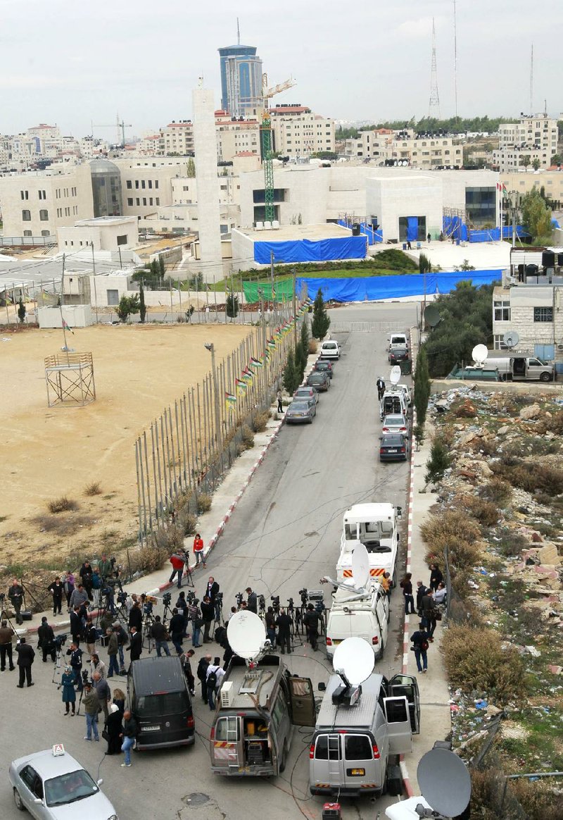 Journalists wait Tuesday on the road leading to the mausoleum of Yasser Arafat in the West Bank city of Ramallah as authorities exhume the former Palestinian leader’s remains in an investigation into his death. 