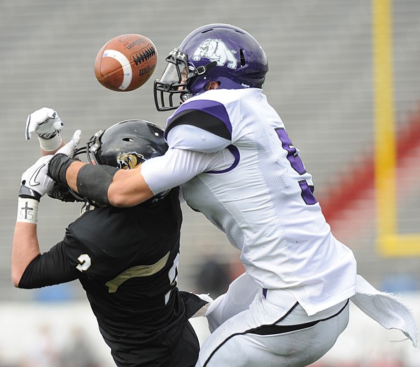 Bentonville’s Chris Mizelle, left, and Fayetteville’s Alex Brignoni reach for a pass during last year’s Class 7A state championship game in War Memorial Stadium in Little Rock. The players return to the title game Saturday. 