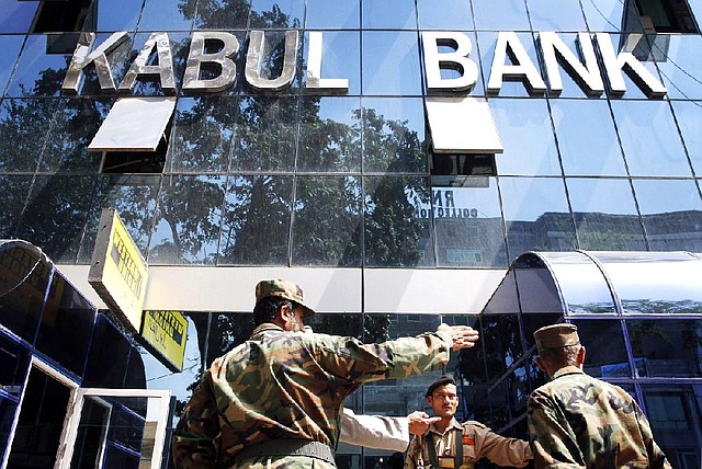 Afghan soldiers chat in front of the main office of Kabul Bank in this 2010 file photo. 