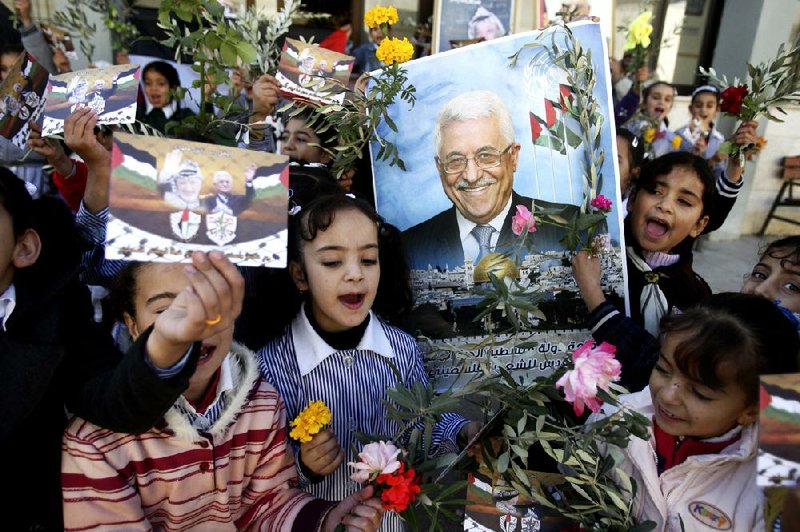 Palestinian schoolgirls hold pictures of President Mahmoud Abbas with Yasser Arafat, flowers and olive branches during a rally Wednesday in the West Bank city of Nablus supporting the Palestinian bid to the United Nations for observer status. 