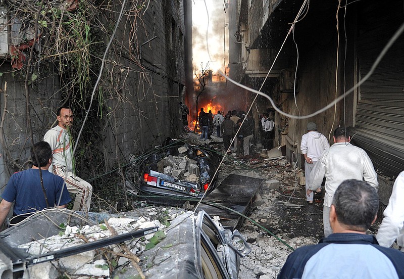 In this photo released by the Syrian official news agency SANA, Syrian citizens gather at an alley destroyed by two cars bombs in the Jaramana suburb of Damascus, Syria, on Wednesday, Nov. 28, 2012.