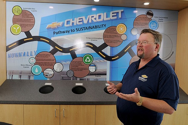 Gan Nunnally, general manager of Nunnally Chevrolet, talks Wednesday about a board showing some of the ways the dealership’s building saves energy, which lead to a LEED certification from the U.S. Green Building Council. 