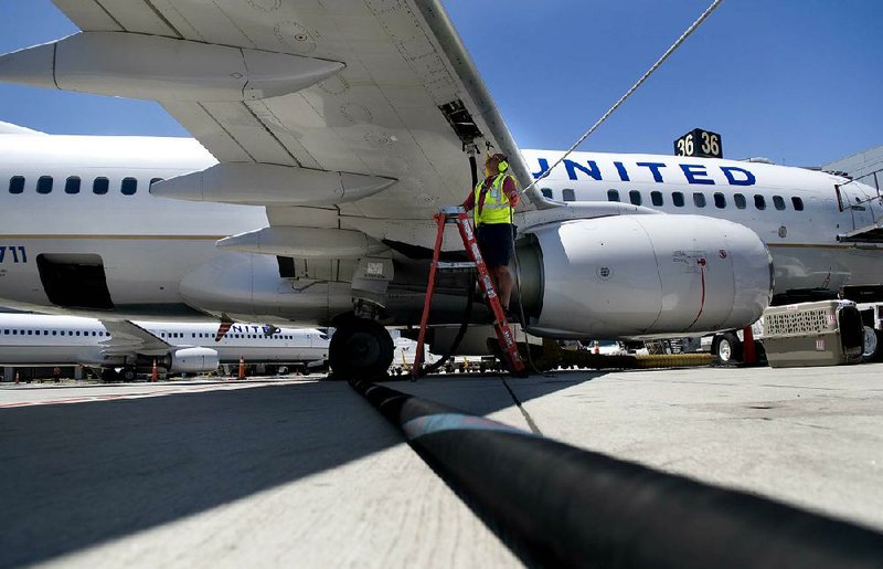 A ground crew member refuels a United Continental plane in June at San Diego International Airport. Merger glitches are still plaguing the airline, now the world’s largest. 