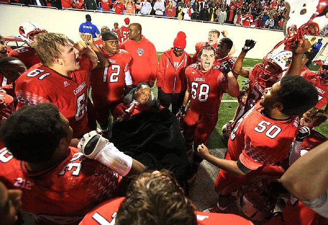 Camden Fairview players celebrate with Khiry Neal (center) following Friday night’s victory over Batesville in the Class 5A championship game at War Memorial Stadium in Little Rock. Neal, a former Cardinals defensive lineman, contracted a staph infection during fall practice in August 2010 and was left a quadriplegic. 