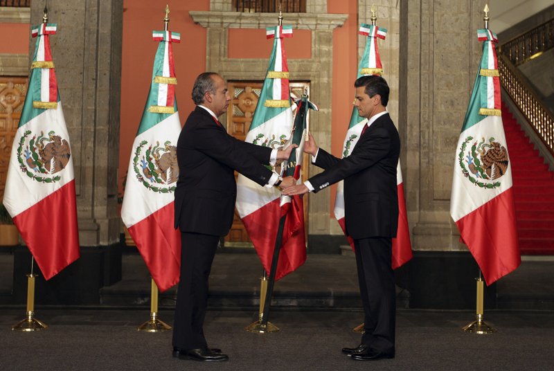 In this image released by the press office of president-elect Enrique Pena Nieto on Saturday Dec. 1, 2012, Mexico's outgoing president, Felipe Calderon, left, gives a Mexican flag to president-elect Enrique Pena Nieto during the official transfer of command ceremony at the National Palace in Mexico City, Saturday Dec. 1, 2012. Pena Nieto will be officially sworn in as Mexico's new President during a ceremony at the National Congress later on Saturday.