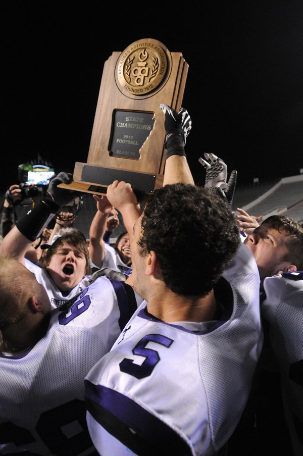 Players hoist the 7A football state championship trophy Saturday, after Fayetteville High repeated as state champions at War Memorial Stadium in Little Rock. Fayetteville beat Bentonville High School, 31-20. 