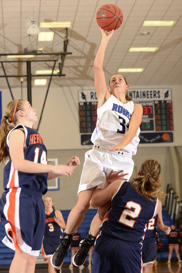 McKinzie James, Rogers High, takes the ball to the basket Saturday over Rogers Heritage’s Ashley Ward at the Great 8 Classic in Rogers. 