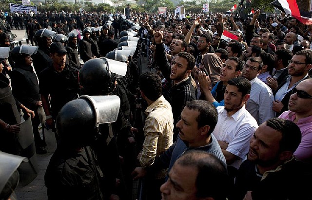 Supporters of Egyptian President Mohammed Morsi confront riot police standing guard near the entrance of Egypt’s top court in Cairo on Sunday. 