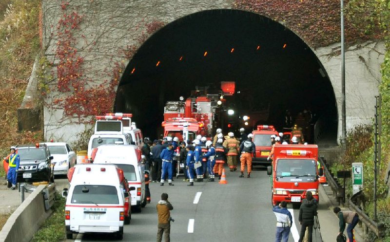 Police and firefighters gather at the exit of the Sasago Tunnel on the Chuo Expressway in Otsuki, Yamanashi prefecture, Japan, on Sunday morning. Parts of the tunnel collapsed early Sunday, trapping an unknown number of vehicles. At least nine people died.