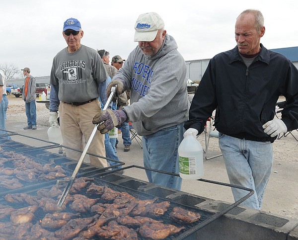 Mark Kruger, from left, Rick Stocker and James Willett grill chicken Saturday to raise money for the Heritage High School’s Future Farmers of America in Rogers. Willett said the benefit chicken cooks, held at Second and Locust streets in Rogers, have raised $40,000 for a variety of organizations this year. Each event raises $1,000 to $1,300 for the benefiting group, Willett said. 