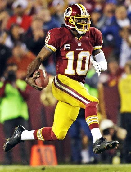 Washington Redskins quarterback Robert Griffin III (above) threw for one touchdown and had a fumble turn into another score, and the Washington Redskins pulled within one game of the NFC East lead with a 17-16 victory over the New York Giants on Monday night.The Redskins improved to 6-6 with their third consecutive victory, tied with the Dallas Cowboys and on the heels of the Giants, who have lost three of four to fall to 7-5. Griffin completed 13 of 21 passes for 163 yards and ran five times for 72 yards, breaking Cam Newton’s NFL record for yards rushing by a rookie quarterback with 642 yards this season. Griffin lost the ball on one of his runs, but it flew into the arms of teammate Joshua Morgan, who ran it in for an early touchdown.