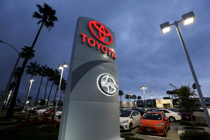 A Toyota dealership sign glows over a car lot recently in Tustin, Calif. A better economy and extra demand after superstorm Sandy lifted U.S. auto sales in November. 