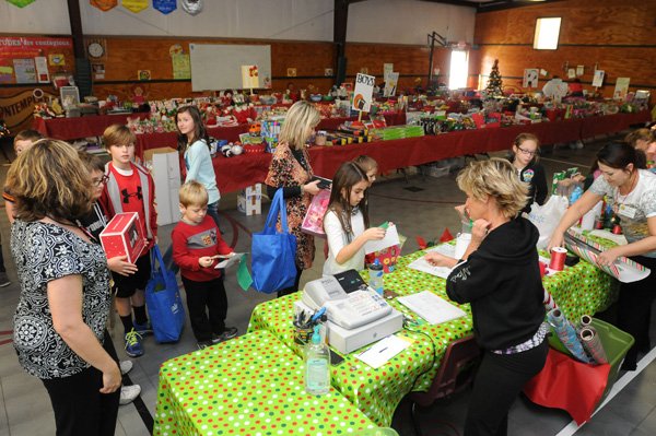 Kindergartners head to the checkout station Monday in the Holiday House at Bellview Elementary in Rogers after shopping for gifts. The temporary gift shop held in the school’s gym is hosted annually by the Parent Teacher Association. 