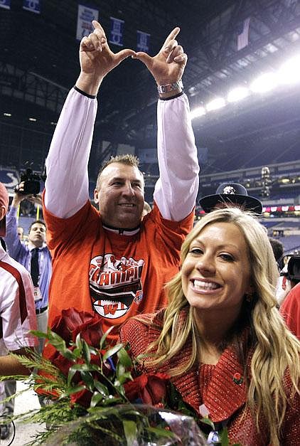 Bret Bielema and his wife Jen rejoice Saturday after Wisconsin’s victory in the Big Ten Championship Game at Indianapolis. Bielema, 42, displays a Wisconsin victory sign, forming a W with his thumbs and index fingers. Today, he will likely be calling the Hogs when introduced as Arkansas’ new coach.

