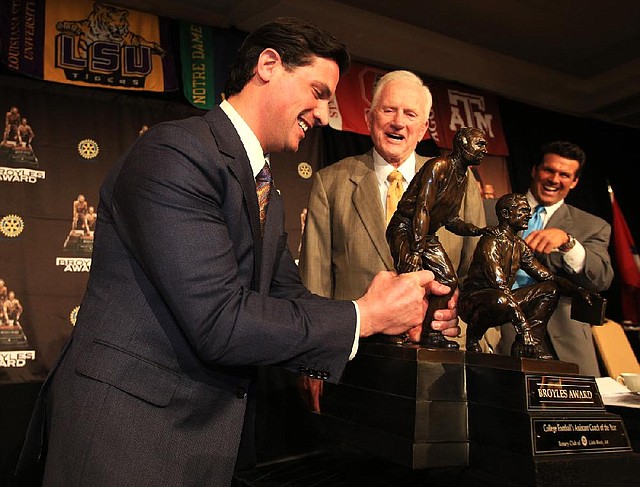 Notre Dame defensive coordinator Bob Diaco (left) tries to lift the Broyles Award trophy he won Tuesday in Little Rock while Frank Broyles, Arkansas’ former coach and athletic director, and Broyles Award executive director David Bazzel look on. Video is available at arkansasonline.com/videos.

