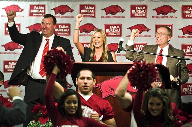 New Arkansas head coach Bret Bielema, left, his wife, Jen, center, and athletic director Jeff Long, right, Call the Hogs during an NCAA college football news conference in Fayetteville, Ark., Wednesday, Dec. 5, 2012. (AP Photo/April L. Brown)