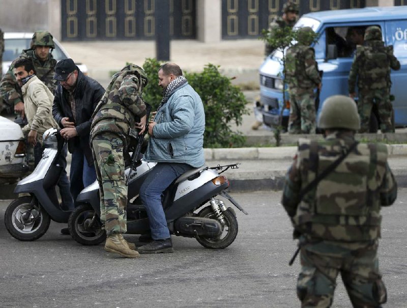 Lebanese soldiers out to calm violence conduct searches Wednesday at a checkpoint in Tripoli. 