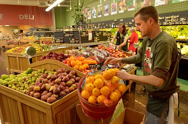 Jeff Alvine, staff member at the Ozark Natural Foods in Fayetteville, puts out fresh fruit Wednesday afternoon. Ozark Natural Foods announced in a news conference Wednesday afternoon they will pay off the building loan early in an effort to save money. The decision to pay off the loan early was debated for the past 16 months among the owners. 