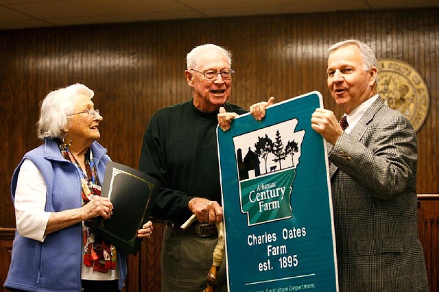 Arkansas Agriculture Secretary Butch Calhoun (right) presents a sign to Charles and Jean Oates of Pottsville on Thursday in Ozark for the Arkansas Century Farm program. 