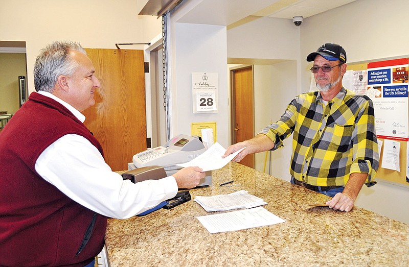 Frank Berryman of Benton, right, receives a copy of his Air Force discharge papers, known as form DD-214, from Saline County Circuit Court Clerk Dennis Milligan. Copies of the form, which is required to receive many veterans’ benefits, can be kept on file at the clerk’s office. Milligan and Garland County Circuit Court Clerk Jeannie Pike encourage veterans to bring a copy of the form to their offices for safekeeping.