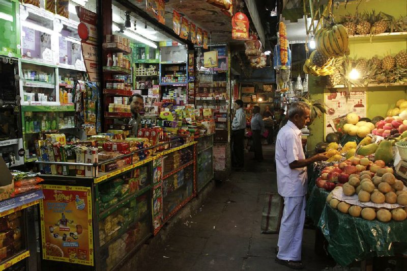 A customer examines fruit at a small retail store in Kolkata, India. India’s Parliament on Friday approved the government’s plan to open up the country’s retail sector to international companies. 