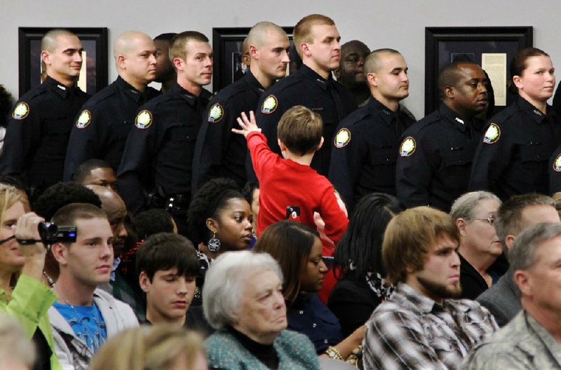 Jayden Palmer, 4, waves to his father, Jeremy Palmer (far left), as he and other members of the latest Little Rock Police Department recruiting class take the oath of service Friday during a graduation ceremony. Jeremy Palmer won the overall top-recruit honor in the class of 31, the largest for the department in several years. More photos are available at arkansasonline.com/galleries.