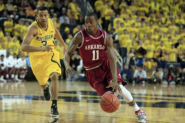 Arkansas guard BJ Young (11) drives around Michigan guard Trey Burke (3) during the first half of an NCAA college basketball game in Ann Arbor, Mich., Saturday, Dec. 8, 2012. (AP Photo/Carlos Osorio)