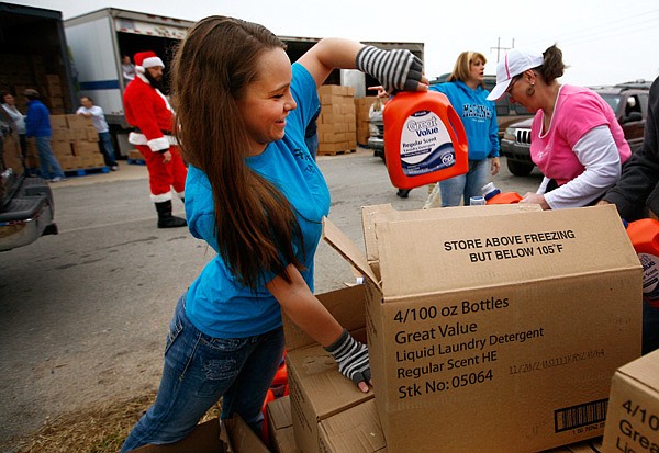 Tabitha Talburt of Garfield pulls laundry detergent Friday during the annual Sharing & Caring of Benton County Christmas distribution at the Benton County Fairgrounds in Bentonville. The event served children’s gifts, household items and food to about 1,800 area families. To watch video of the event, go to nwaonline.com/xx/videos/2012/ dec/07/7913. 