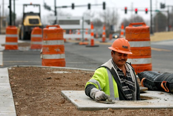 Carlos Feliz with APAC works Friday in a manhole along East Central Avenue near the intersection with Northeast I Street along Southwest I Street in Bentonville. 