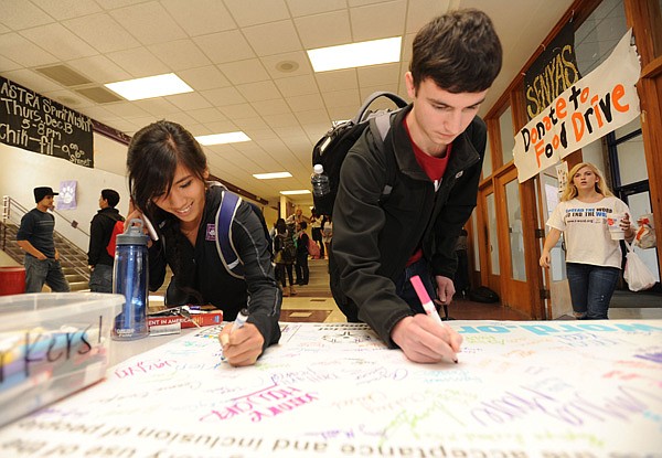 Mia Bautista, left, and Jonathan Main, Fayetteville High School seniors, sign Wednesday a pledge to stop using the word “retarded” while taking part in a national campaign organized by Special Olympics and backed at the school by the Bulldog Partners Club in the Bulldog Lobby at the school. 