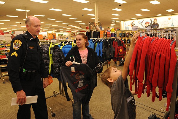 Cpl. Stan Cain with the Rogers Police Department shops Saturday at Pinnacle Hills Promenade with Shannon Rossiter of Lowell and her son, 6-year-old Zechariah Rossiter. Several Rogers officers took part in the annual “Shop with a Cop” event. 