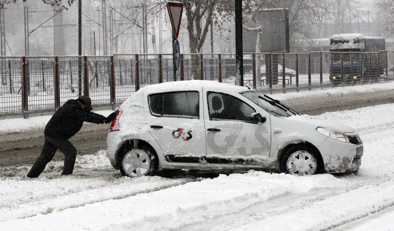 A man pushes a car on a snow covered street in Belgrade, Serbia, Sunday, Dec. 9, 2012. Freezing temperatures and heavy snowfall have killed at least 5 people and caused travel chaos across the Balkans.