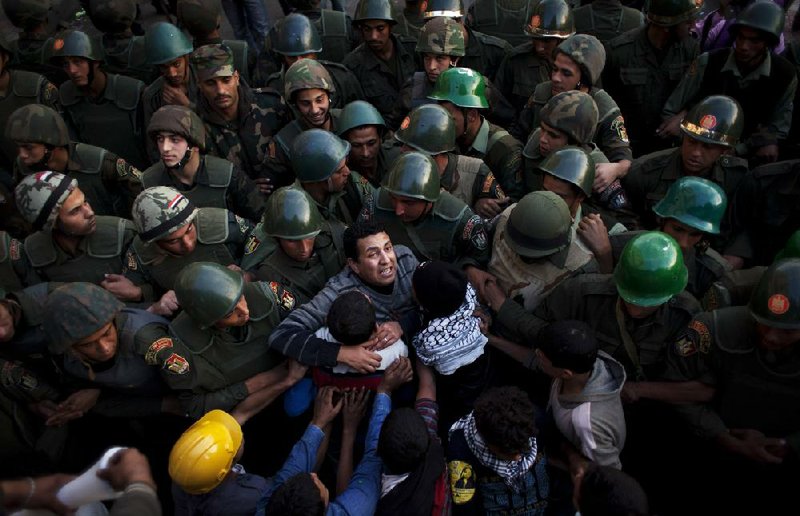 Protesters in Cairo push Egyptian soldiers standing guard Sunday in front of the presidential palace. 