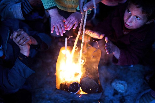 Children in Azaz, Syria, warm themselves Sunday at a refugee camp near the Turkish border. At least 45 people were killed in fighting in Syria on Sunday, according to a British-based opposition activist group. 