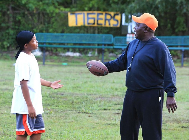 Ed Johnson, better known as Coach Ed, questions Dylan Lowery, 12, the varsity captain of the Sunset Tigers, about why he left his helmet at home before a practice at their field in Little Rock’s Southside Park on Sept. 19. 