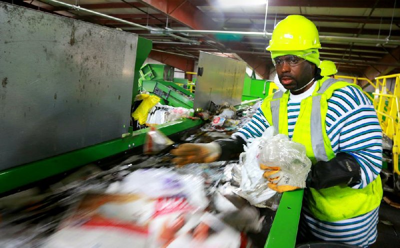 Larry Clark grabs plastic items Friday from a fast-moving conveyor belt at Waste Management’s recycling facility on Sloan Drive in Little Rock.


