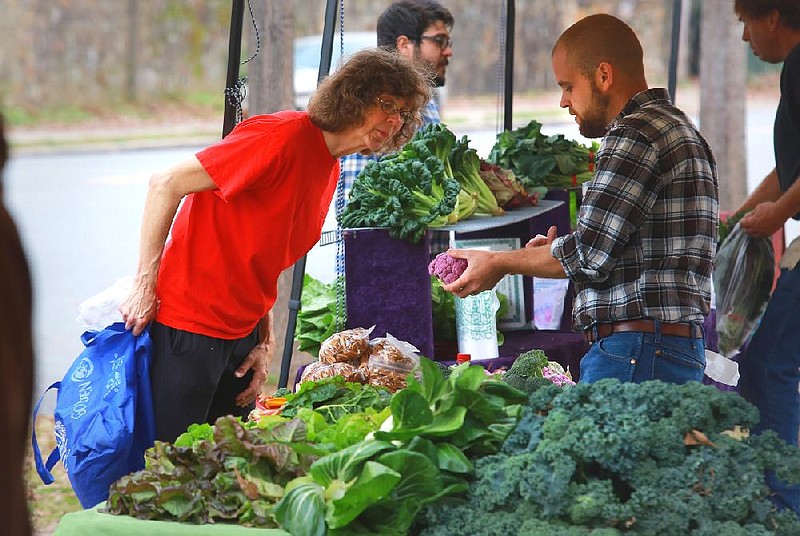 12/8/12
Arkansas Democrat-Gazette/STEPHEN B. THORNTON
Lucy Sauer, left, inspects produce from Josh Forster Saturday morning at the Hillcrest Farmers Market on Kavanaugh Blvd. in front of Pulaski Heights Baptist Church. The market will continue each Saturday throughout the winter, moving inside the church as weather requires. 