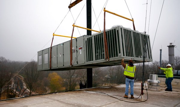 Sean DePeel, left, with Barbee Equipment and John Doyle with Action Mechanical help Saturday guide a heating, ventilation and air conditioning unit to the rooftop of the Benton County Administration Building in Bentonville. 