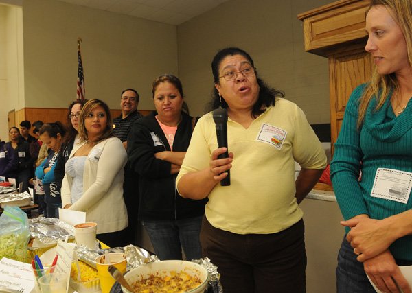 Carmen Contreras, second from right, tells the Padres gathering on Thursday at Grimes Elementary School about the dish she brought to the meal. At right is Reagan Duran, a parent who also brought food for the Rogers event. 