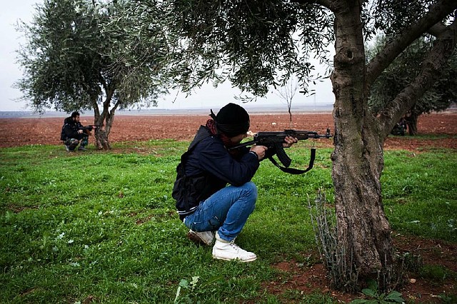 Free Syrian Army fighters take cover Monday behind trees outside a military base near Azaz, Syria. 