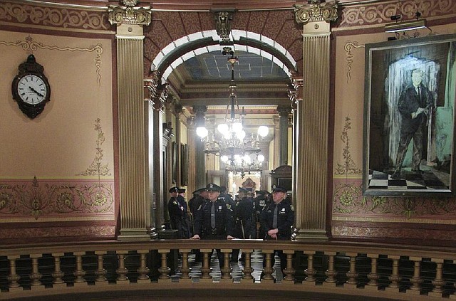 Michigan State Police officers stand on the Senate side of the state Capitol in Lansing, Mich., on Monday. 